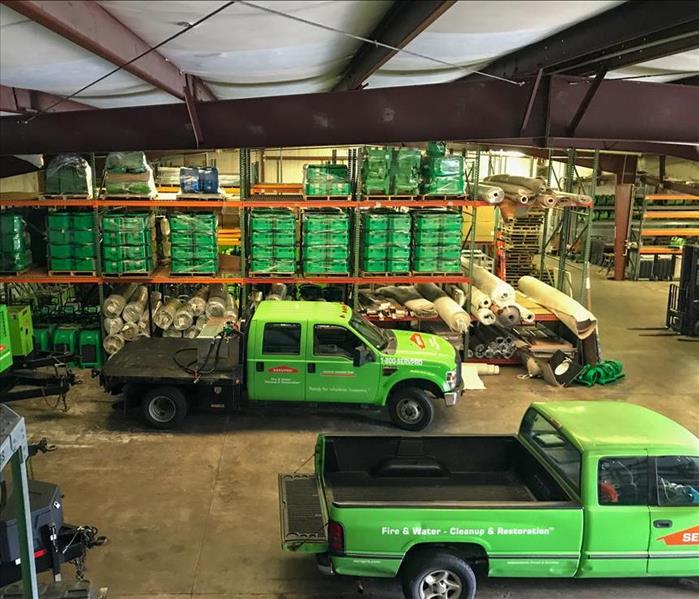 Two green trucks in the SERVPRO warehouse.
