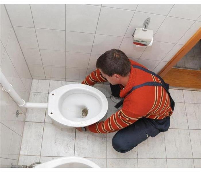 Plumber replacing broken toilet in a washroom
